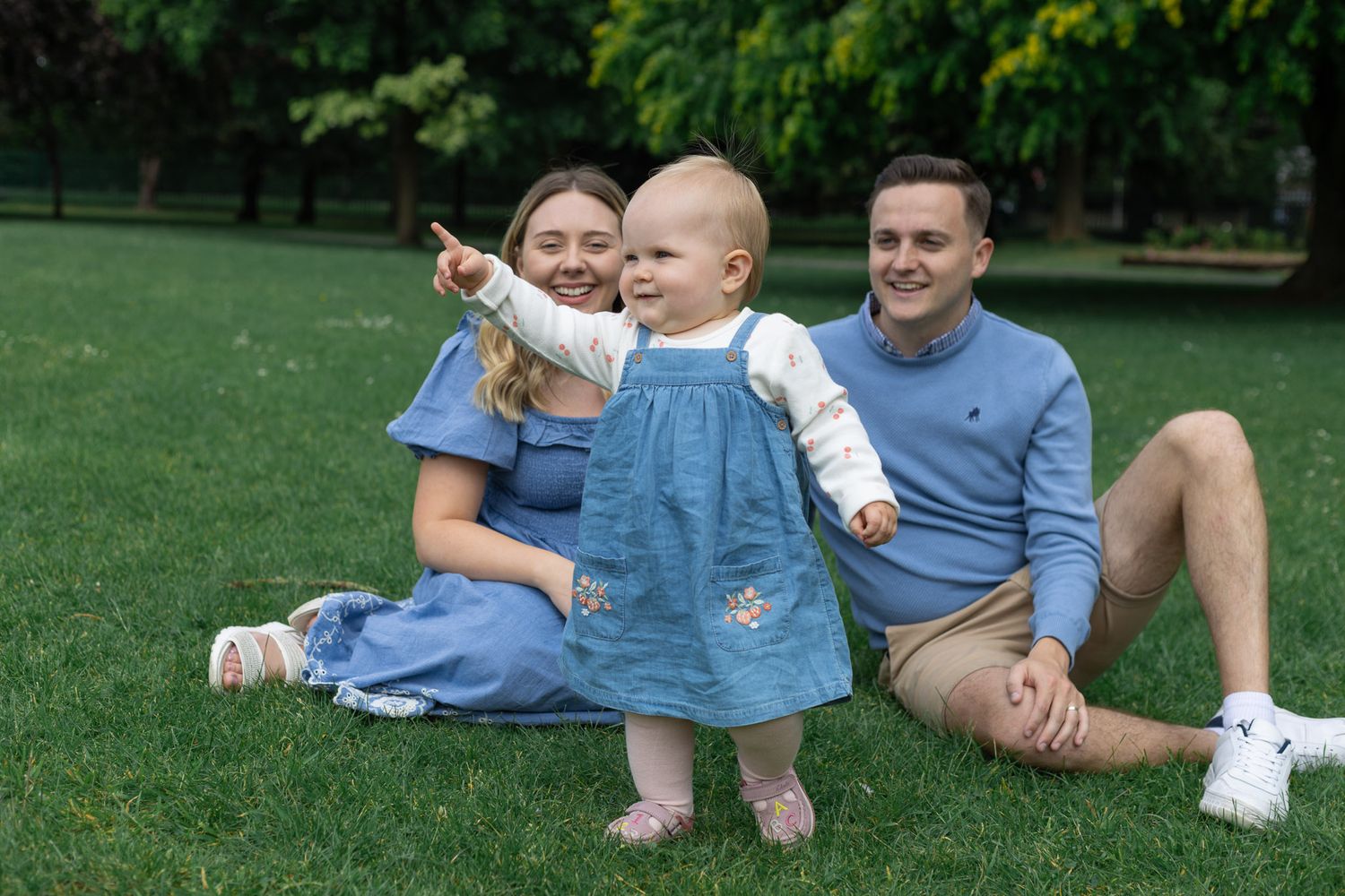 A family enjoys playful moments together during an outdoor photo session in matching blue clothing.