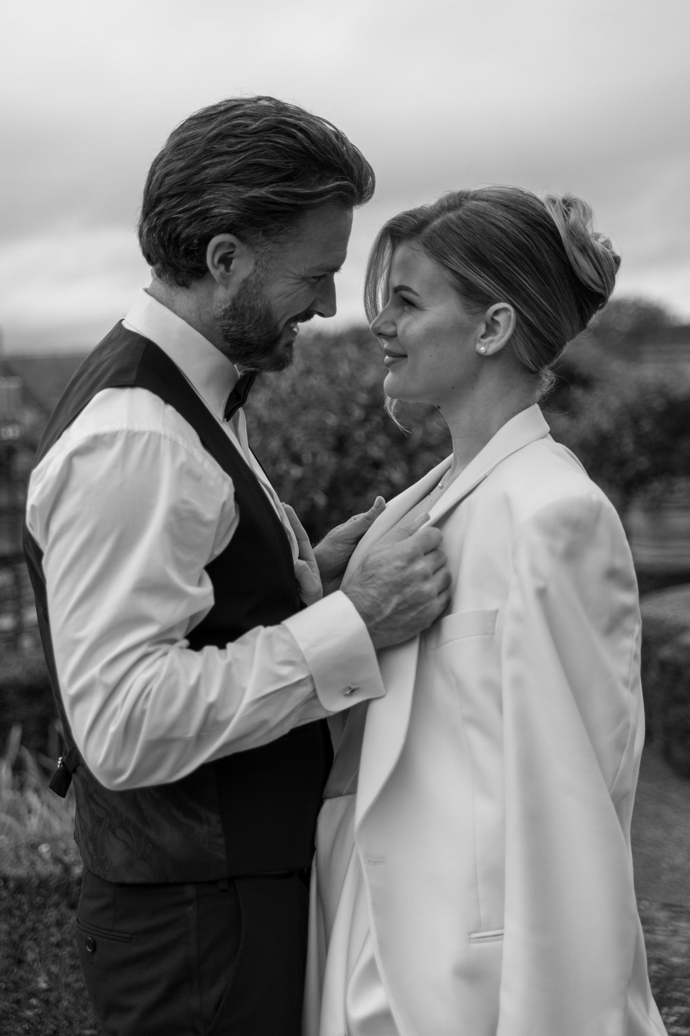 Black and white series of romantic couple embracing against cloudy sky.