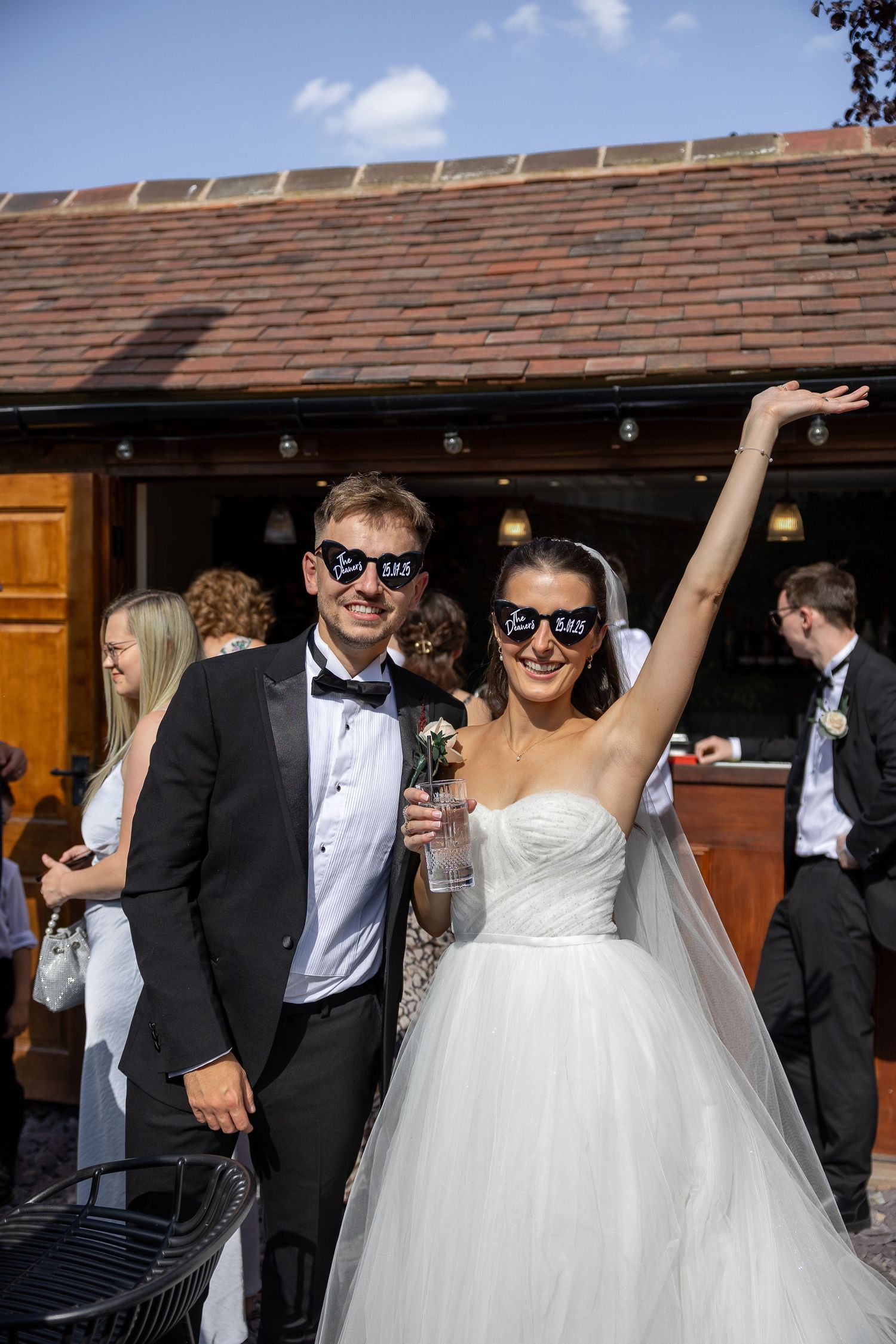 A bride and groom wearing sunglasses share a fun moment together during their wedding celebration.