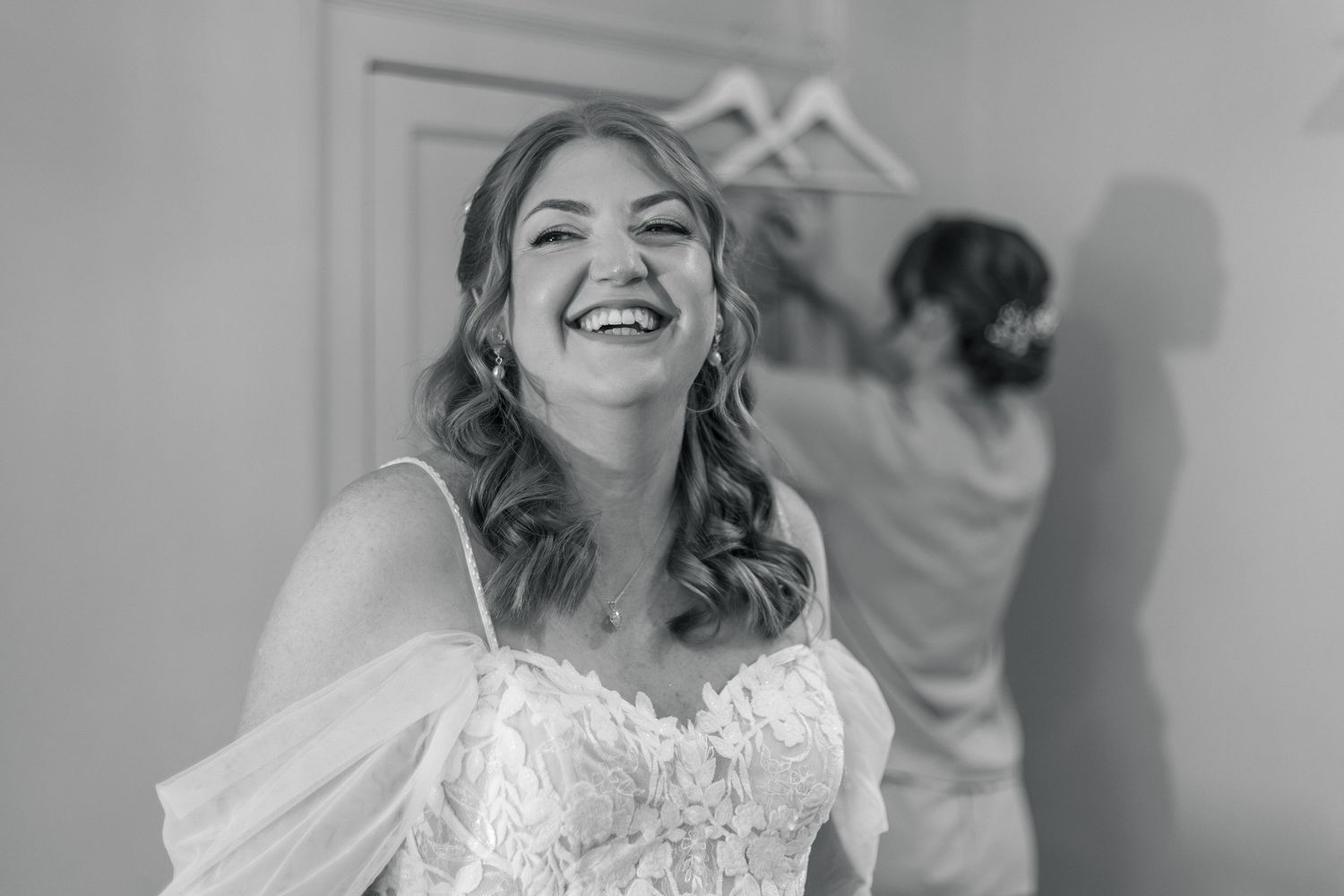 Bride laughing joyfully in lace wedding dress during bridal preparations, black and white photo. Bath.