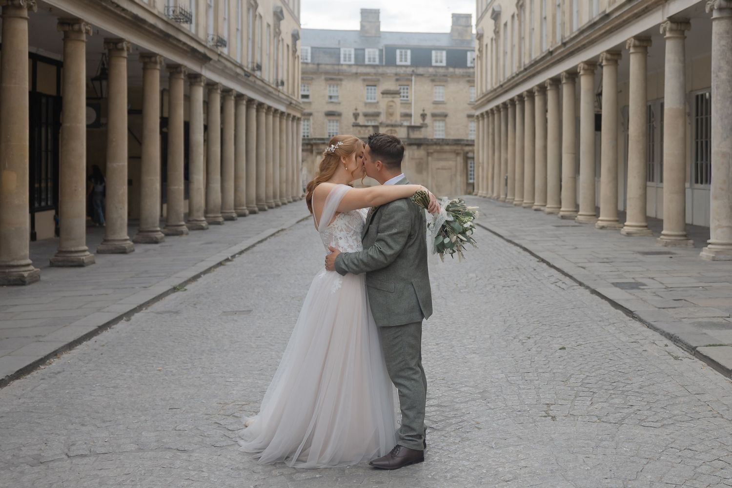 Bride and groom sharing a romantic kiss at the Palais Royal colonnades in Paris on their wedding day.