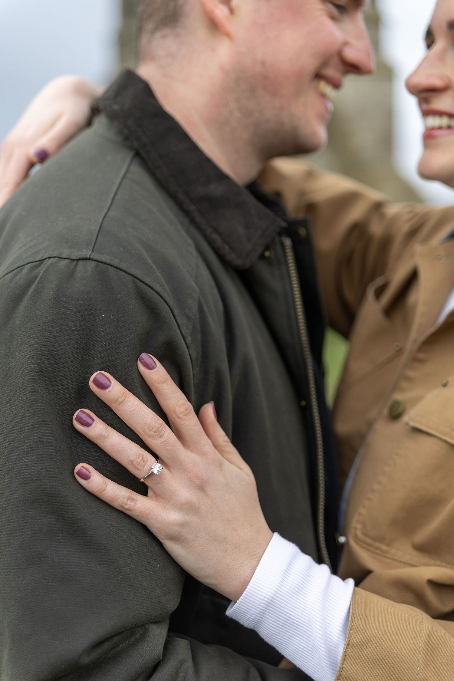 A close-up sequence showing a hand with pink nail polish displaying an engagement ring against a dark jacket.