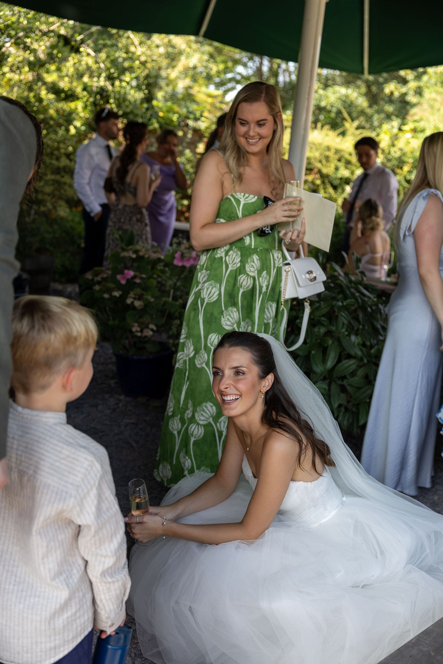 A bride in a white ball gown dances with guests under an outdoor tent at a wedding reception.