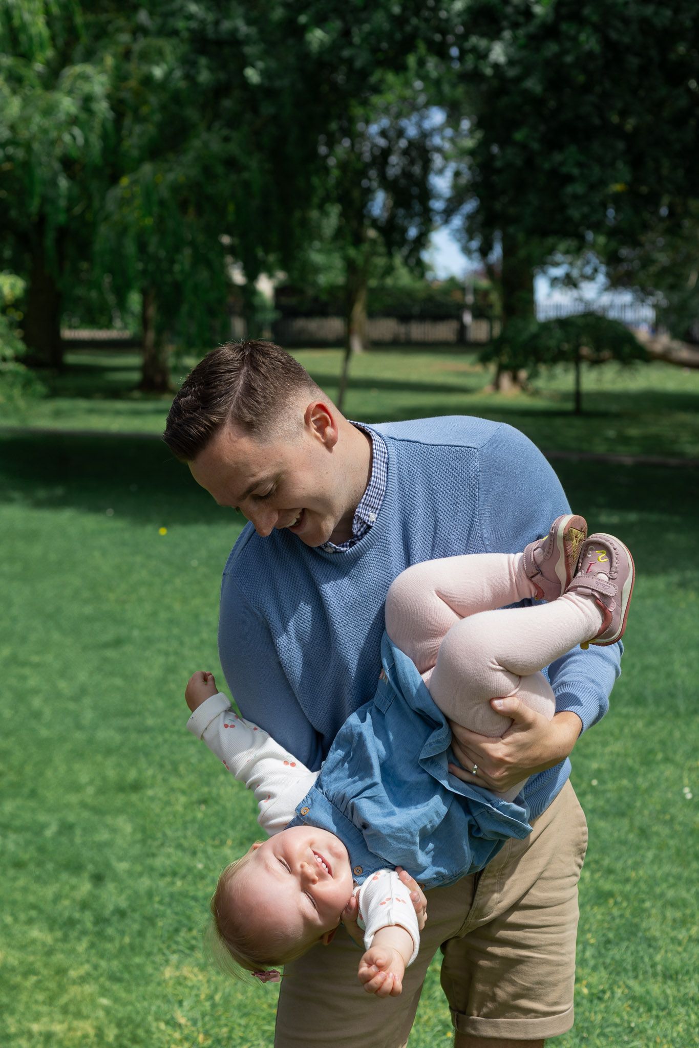 Playful moments captured between parent and child in a sunny park setting.