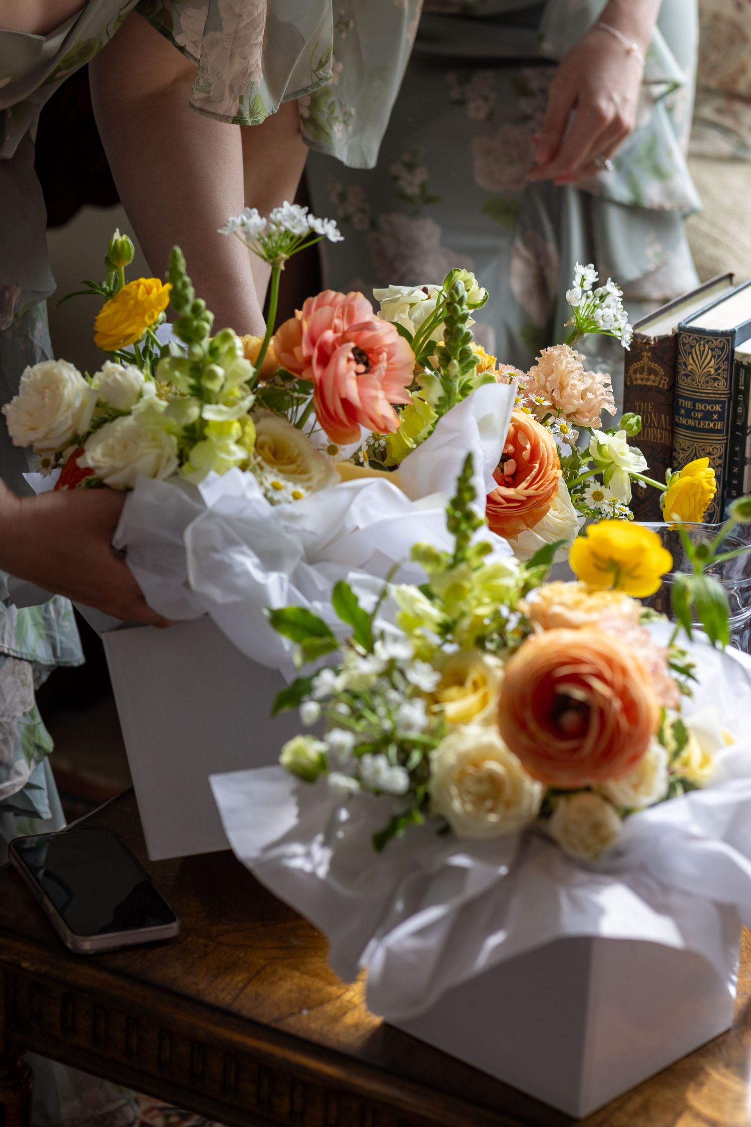 White gift boxes filled with colorful wedding flowers arranged on wooden table.