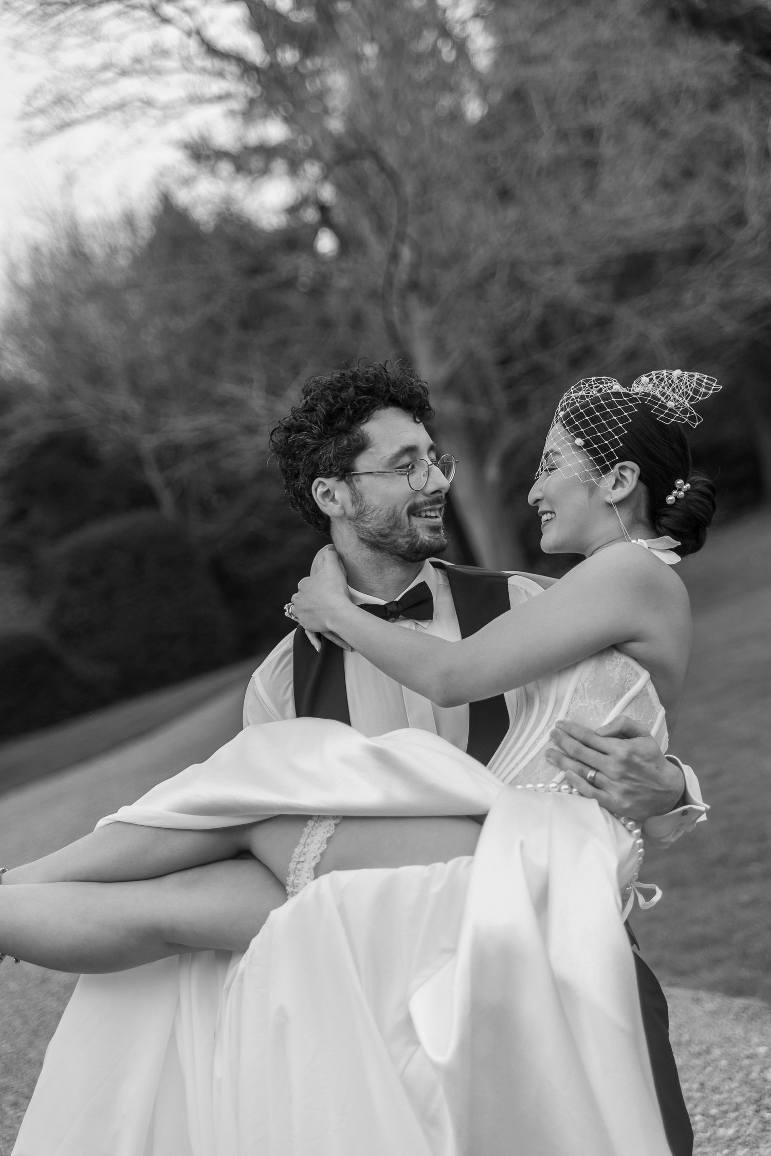 A couple in white embracing and dancing together in a black and white outdoor portrait.