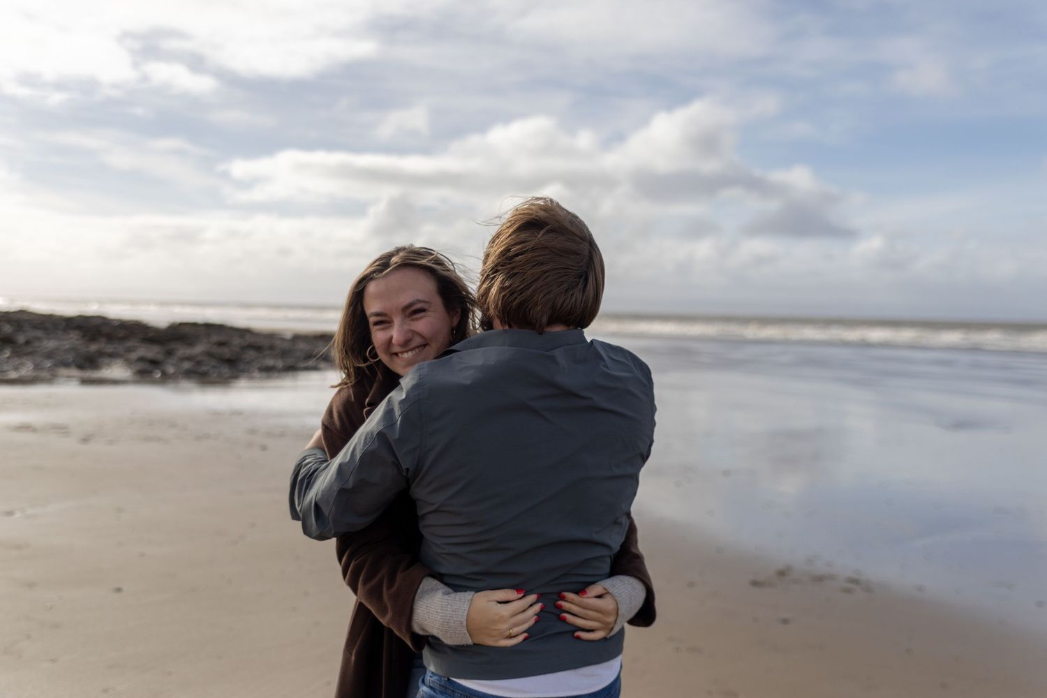 Candid documentary style image of a couple warmly embracing on a beach by Sally Gambling, Wiltshire weddings photographer