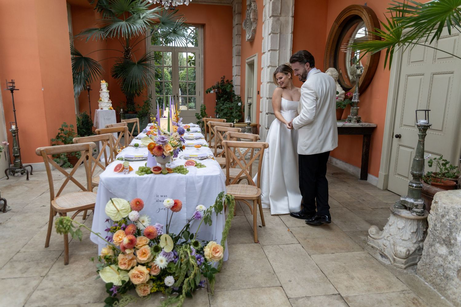 Wedding reception setup at a Euridge Manor Wiltshire wedding with peach walls, elegant table settings and tropical greenery.