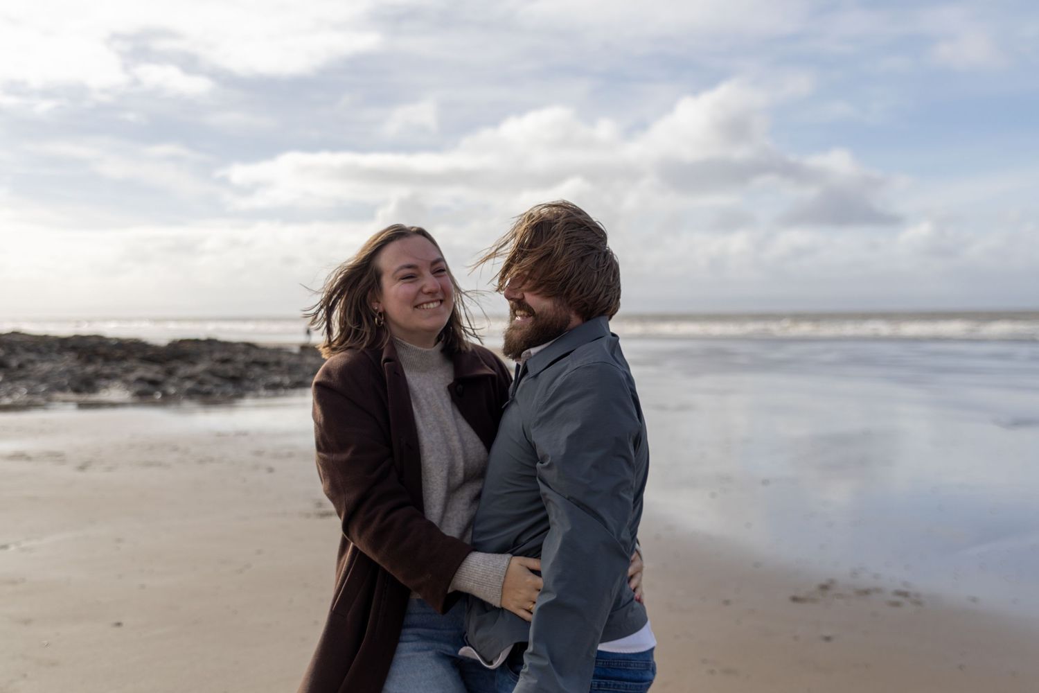 Wiltshire weddings photographer Sally Gambling capturing a couple laughing together during an intimate moment on an overcast beach.