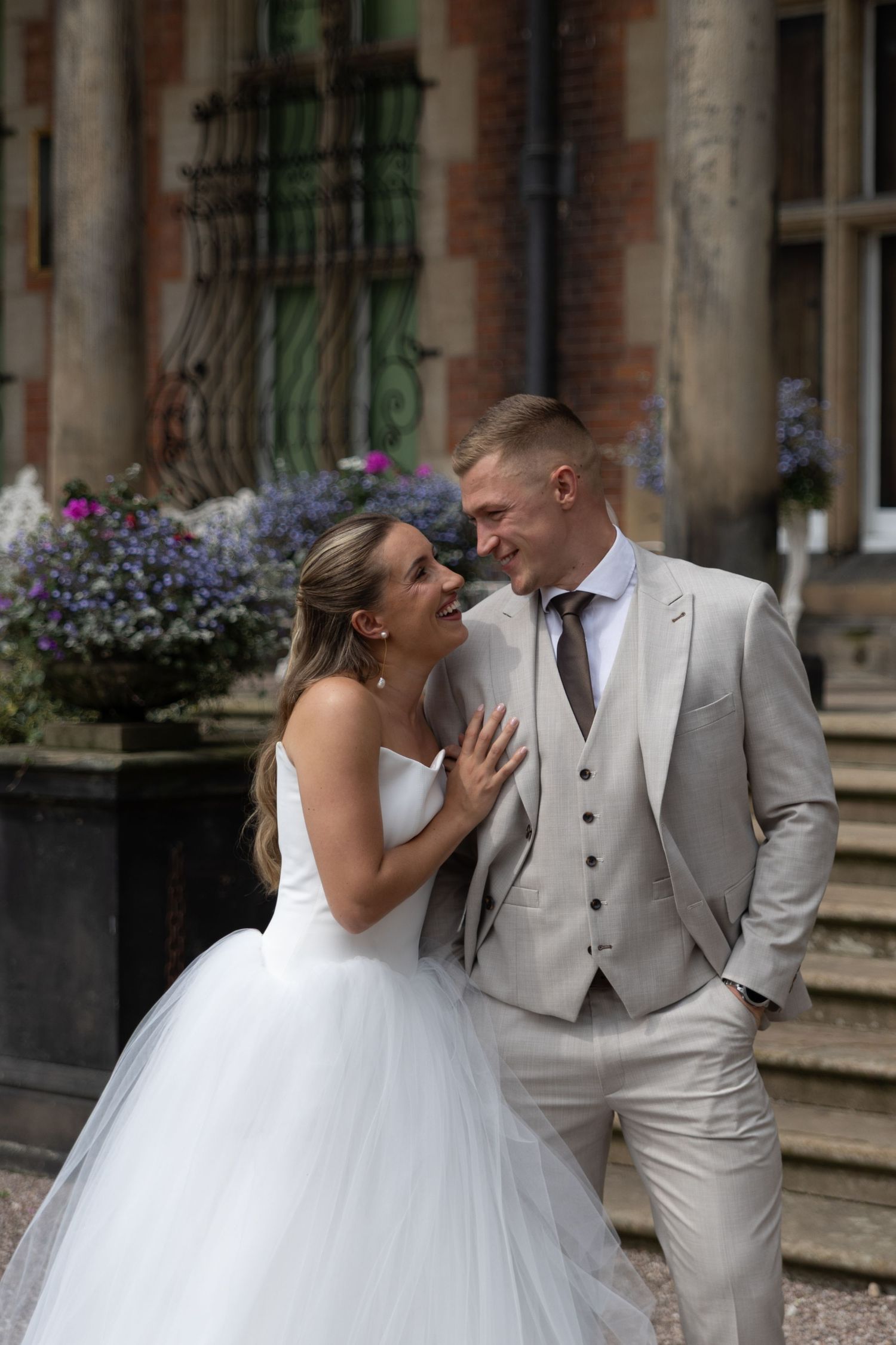 A series of playful wedding portraits taken in front of a stately manor with flower boxes.