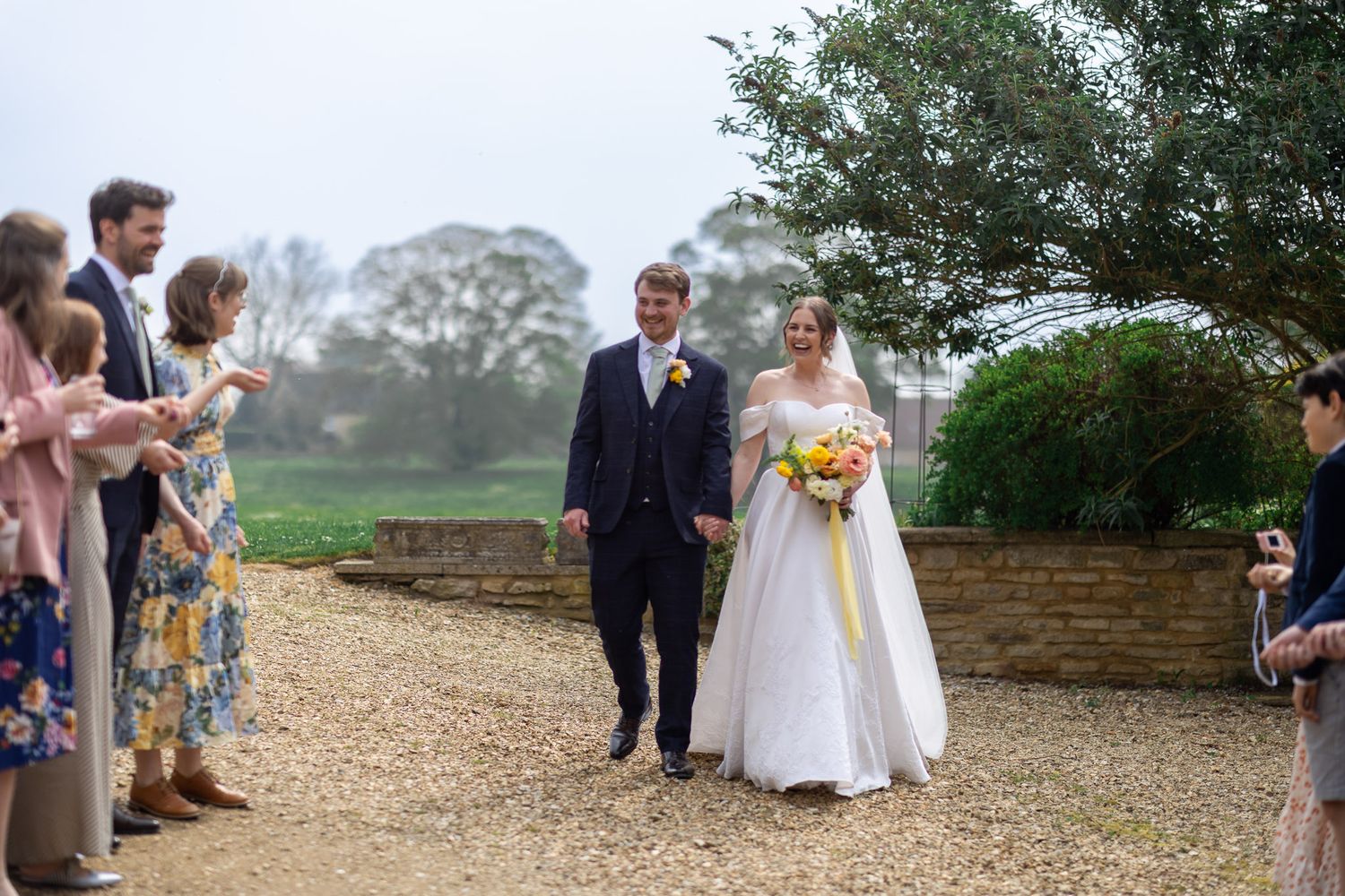 Wedding guests line a gravel path as newlyweds walk through on their special day.