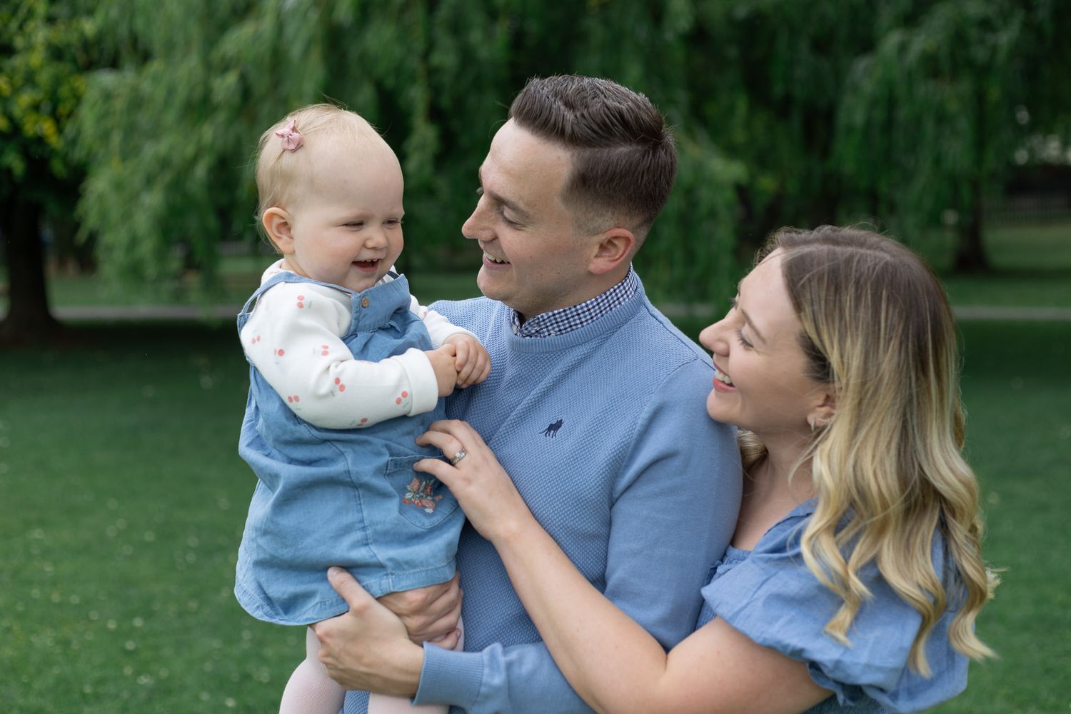 Family in coordinating blue outfits enjoying a playful moment outdoors.