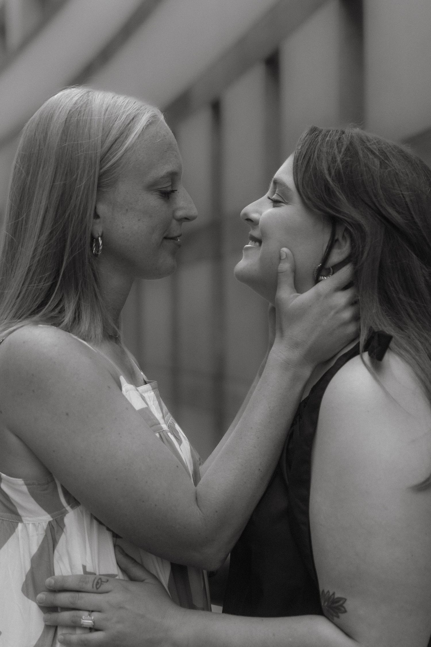 Black and white photo of two women sharing a tender moment, one touching the others face.