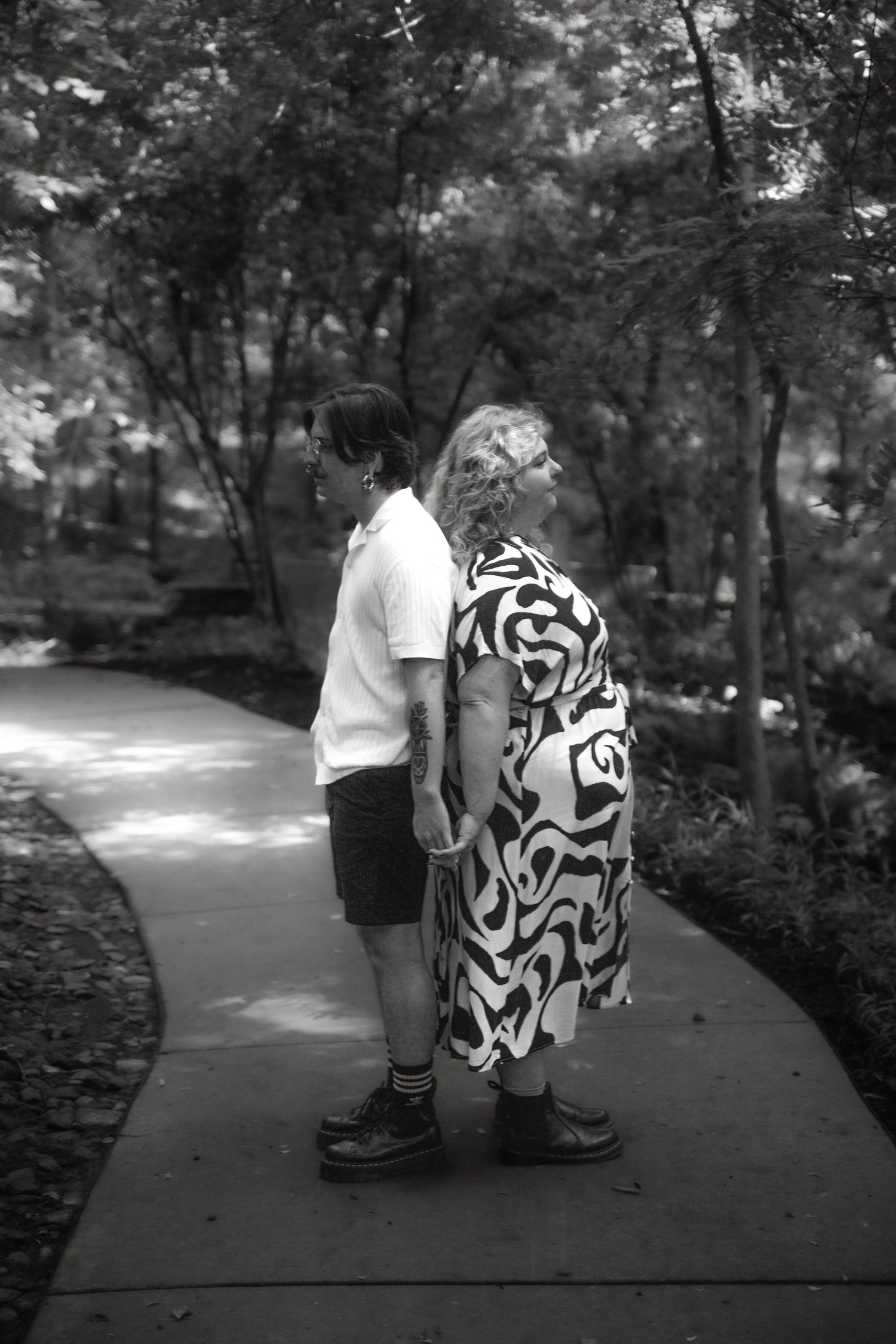 Black and white photo of two women holding hands on a garden pathway.