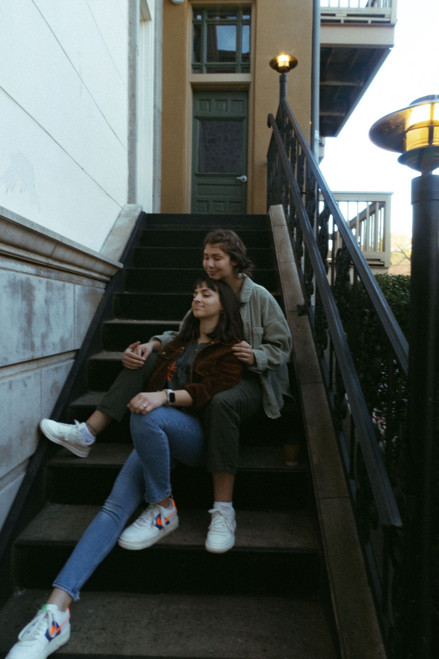 Young couple sitting closely together on outdoor stairs in casual clothing.