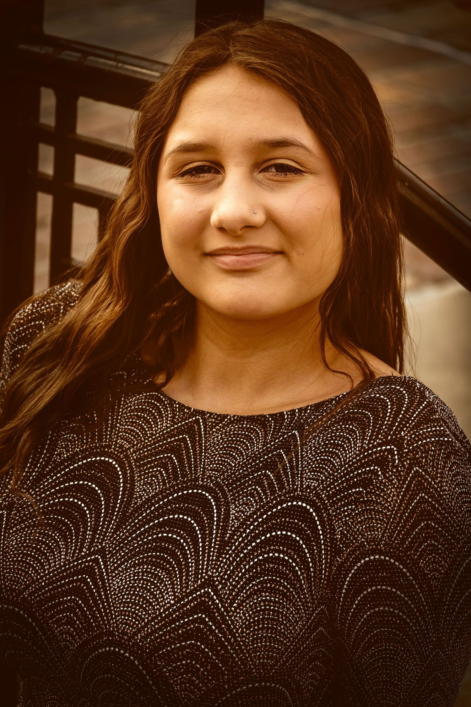 Outdoor portrait of a woman photographed in soft natural light with a warm, neutral background.