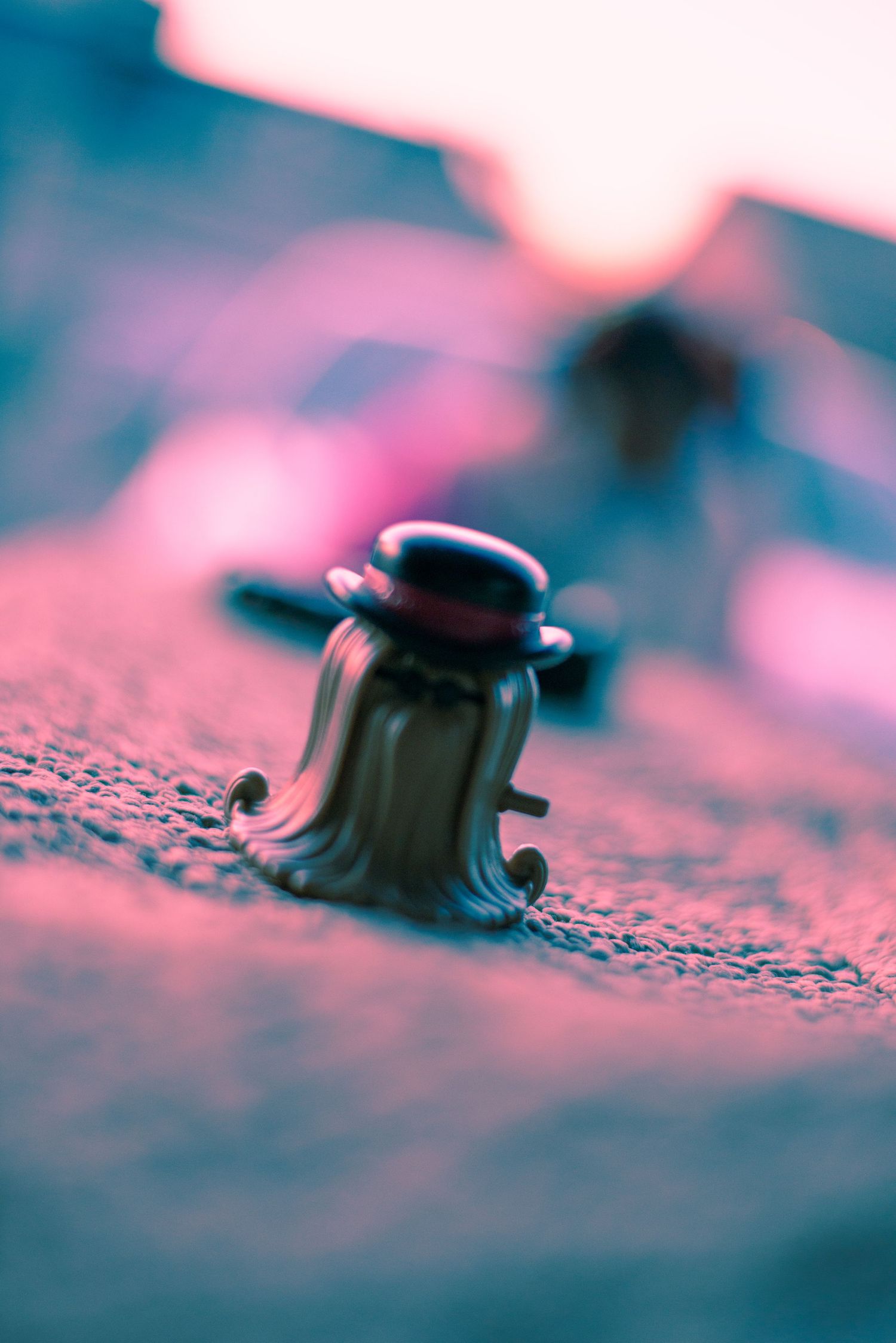 Macro photography of a small metal clip or fastener with pink and blue lighting effects.