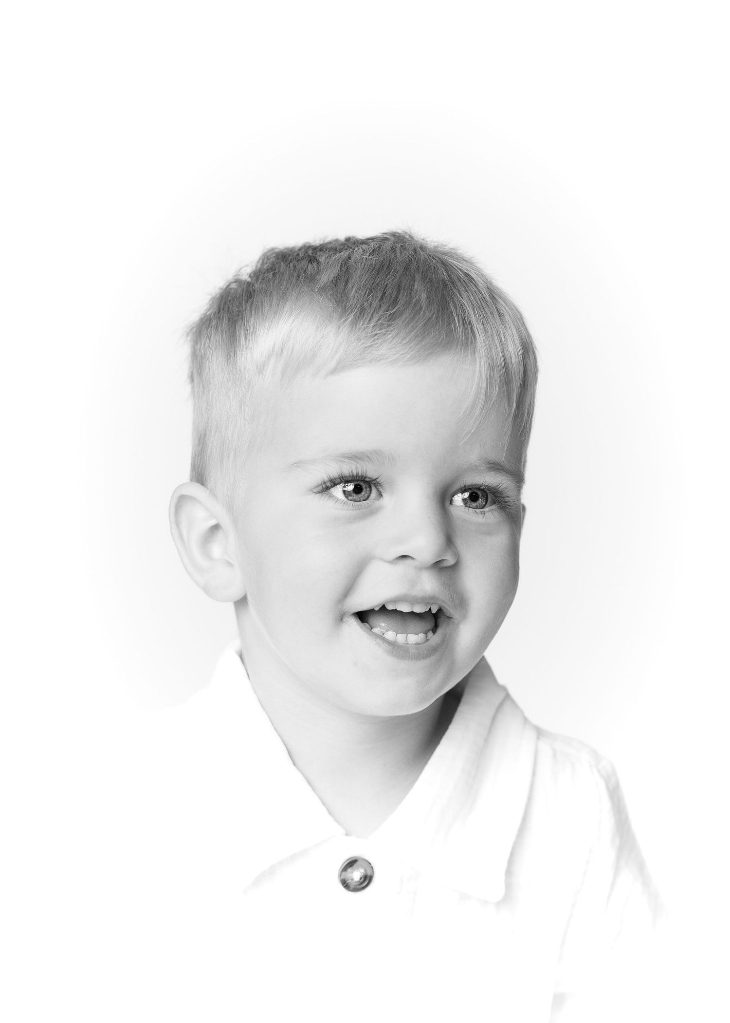 Black and white portrait of a smiling young blonde boy wearing a white polo shirt.