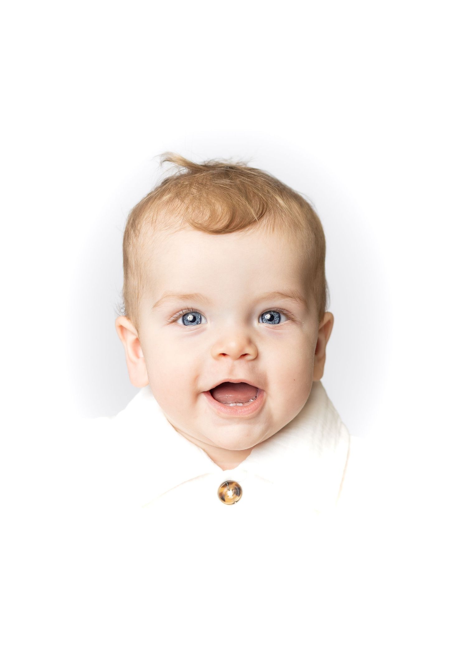 Smiling baby with blue eyes and light hair wearing a white outfit, portrait photo on white background.