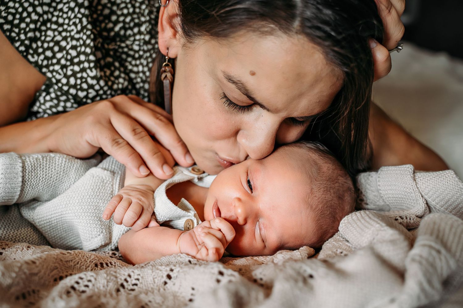 mom kissing newborn baby photo