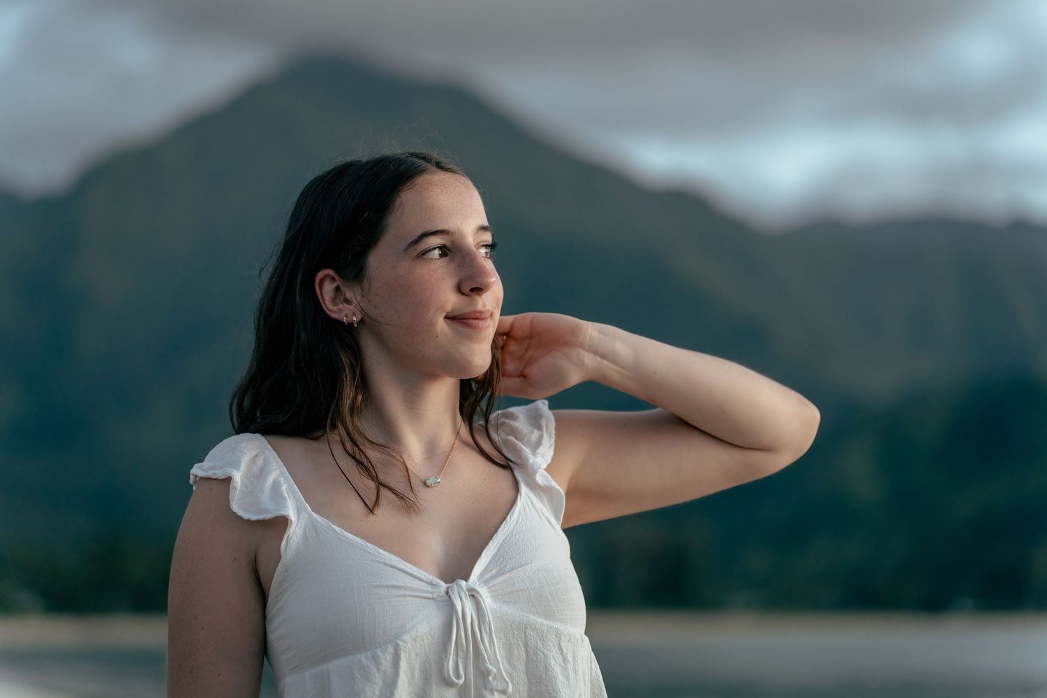A person in a white summer dress gazes into the distance against a backdrop of misty mountain peaks.