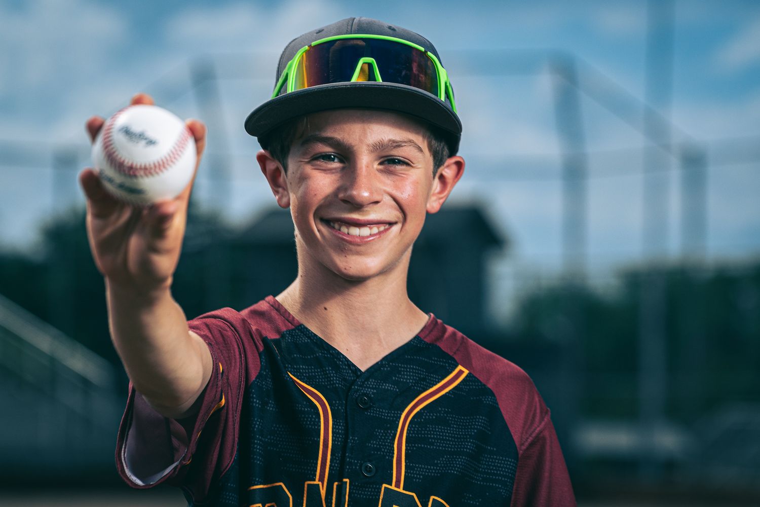 Baseball player in maroon and yellow uniform displays baseball technique while training outdoors.