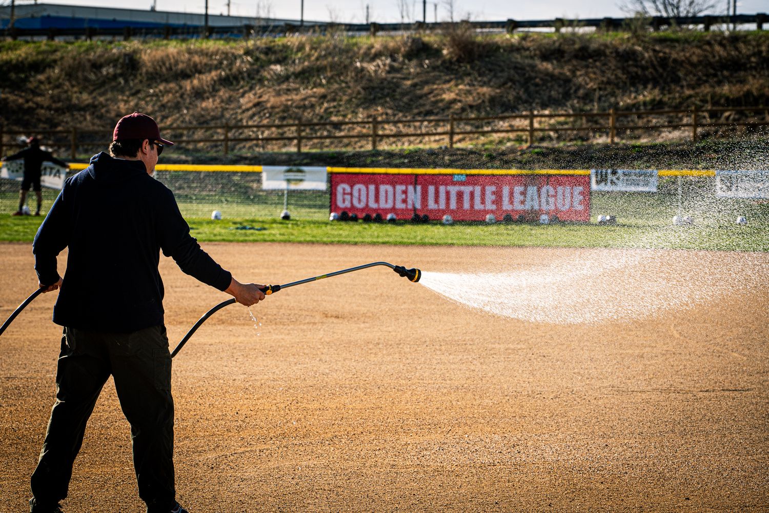 Youth baseball game action shot showing a close play at home plate with umpire making the call.