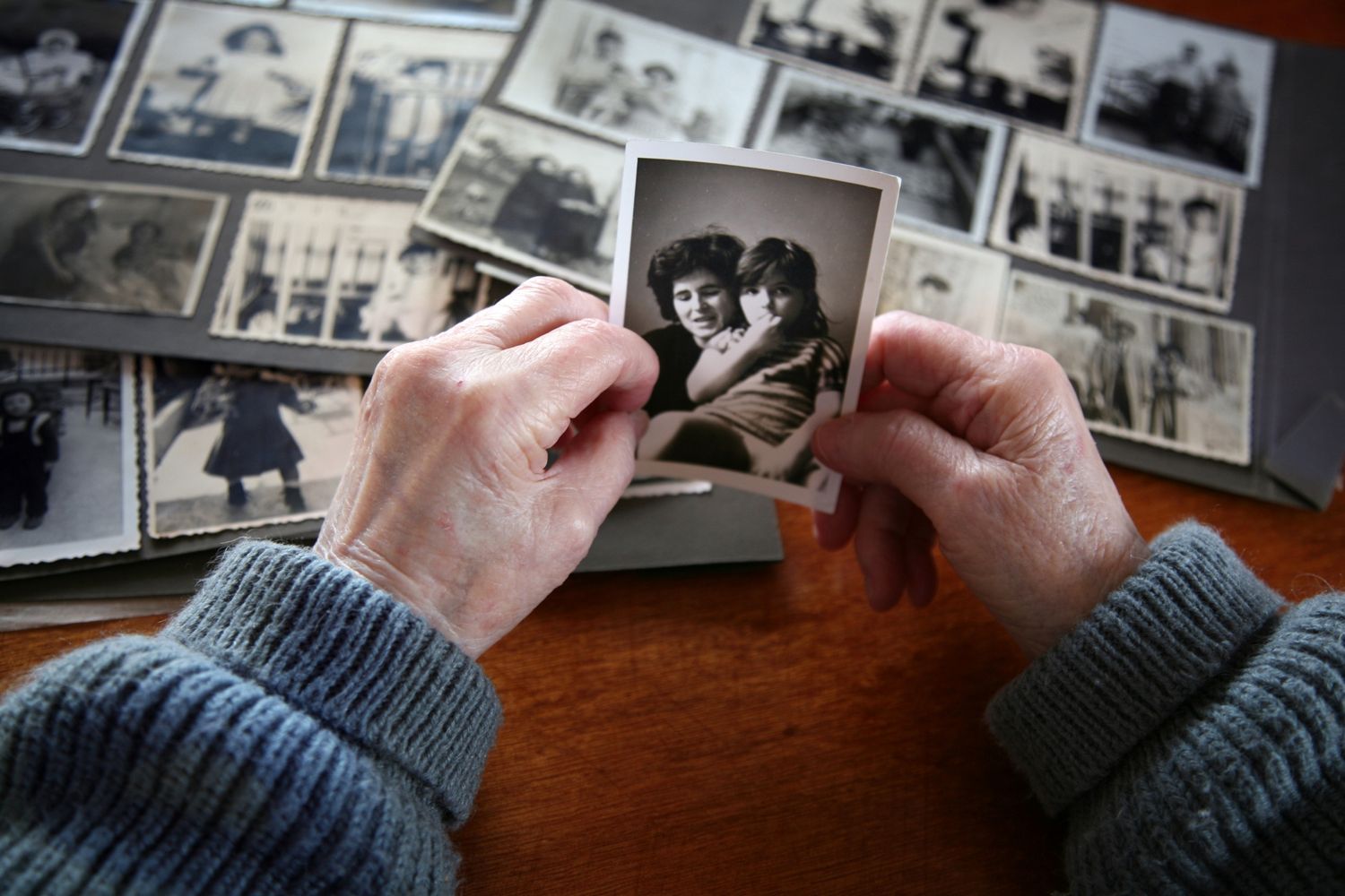 elderly person looking and holding old photograph