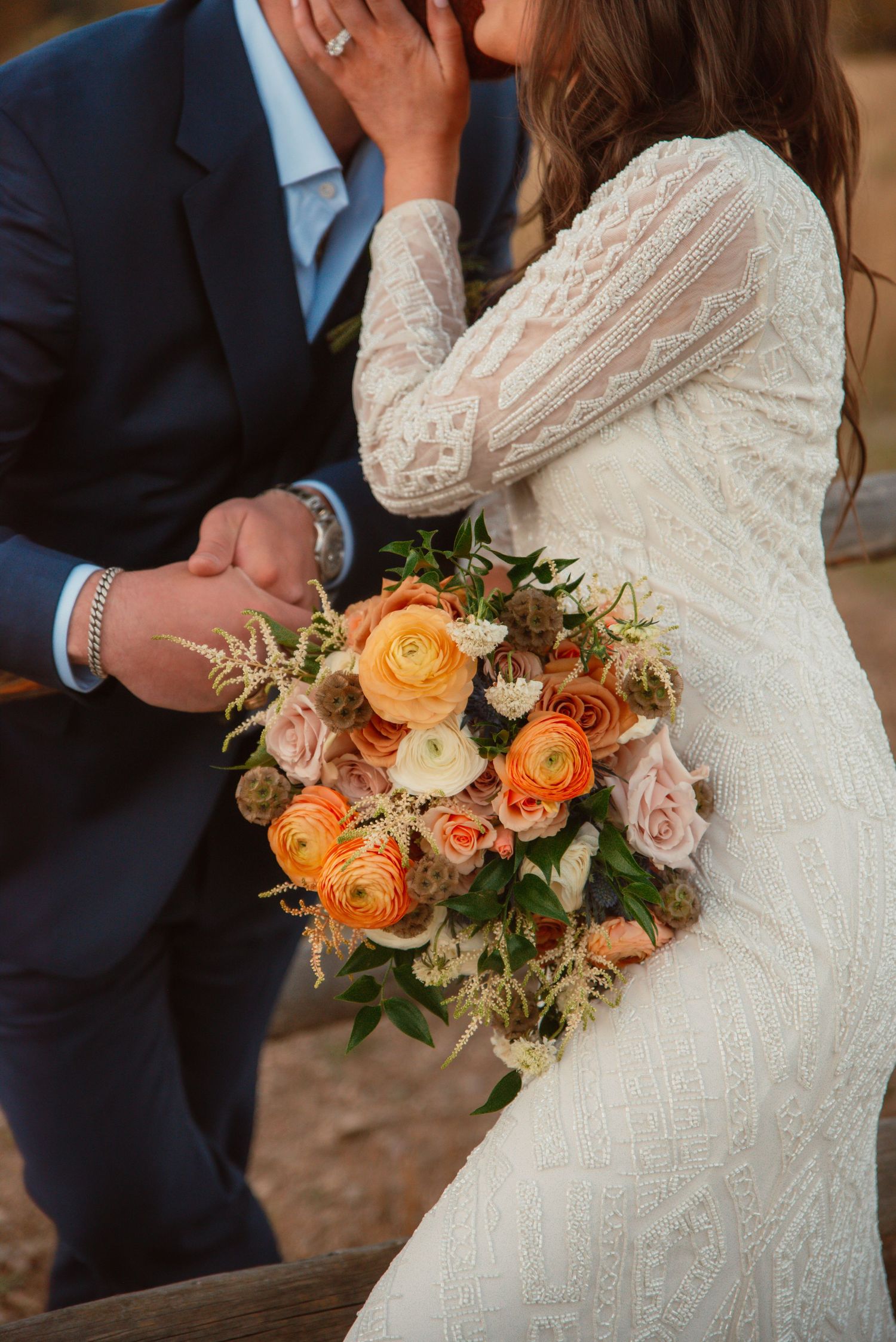 Beautiful bridal bouquet with orange and peach roses alongside elegant wedding attire.