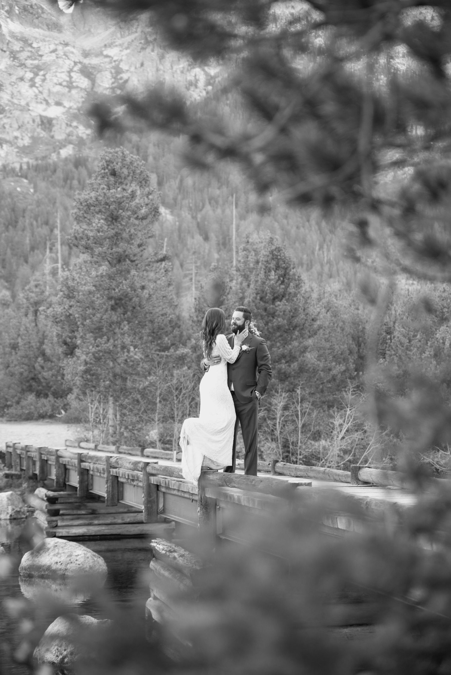 Romantic black and white photo on rustic wooden bridge with mountain scenery.