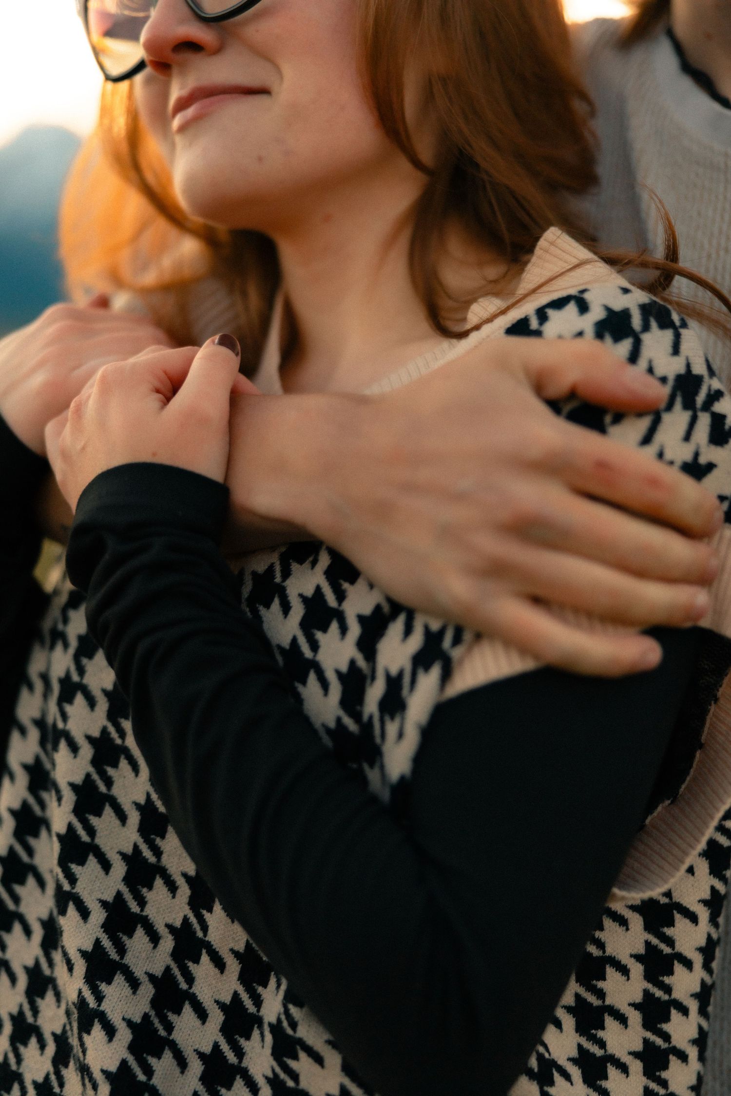 Close-up of a couple embracing, mans hands gently resting on womans shoulders in warm sunset light.