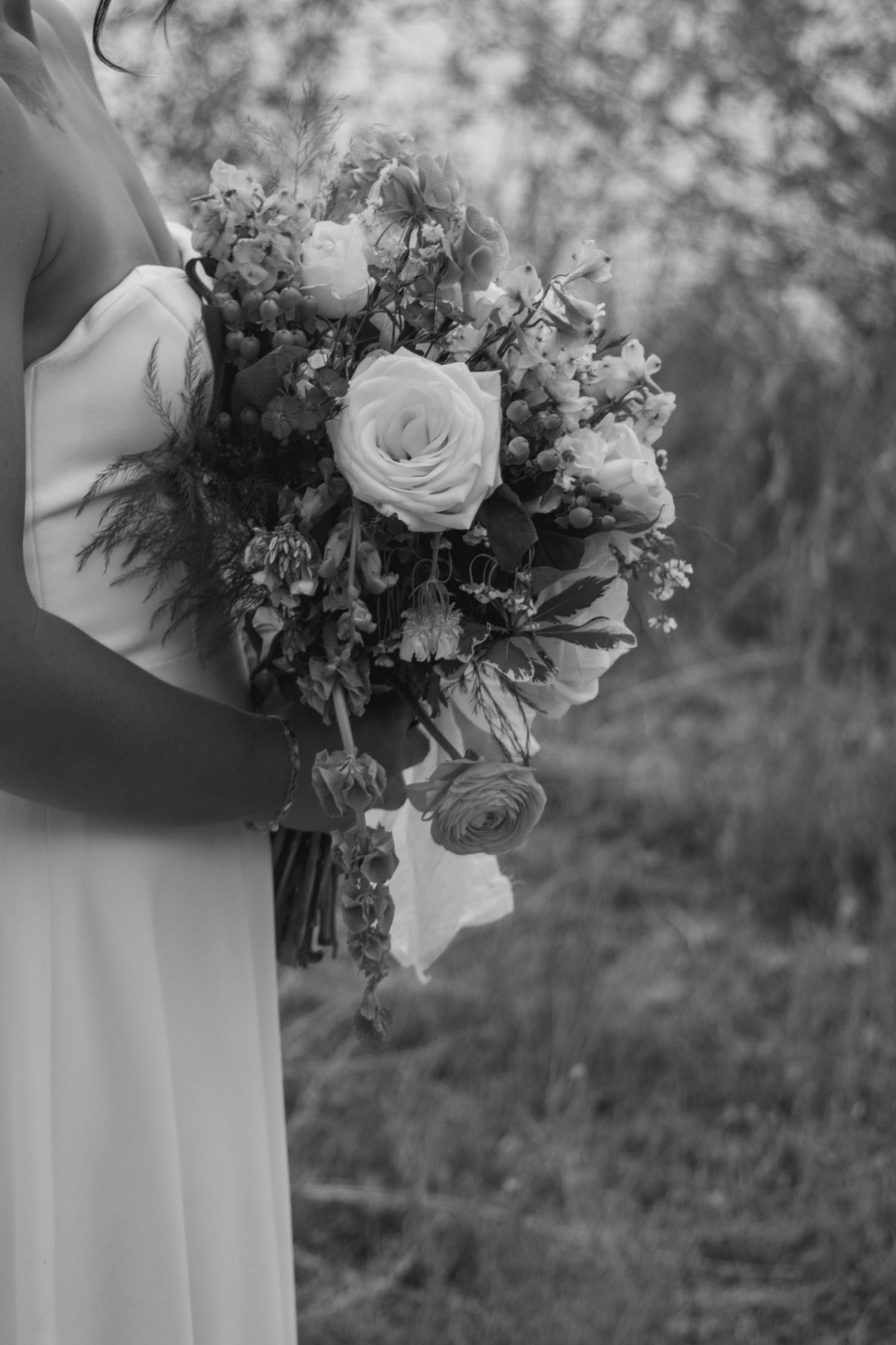 Black and white detail of elegant wedding bouquet with roses and mixed flowers.