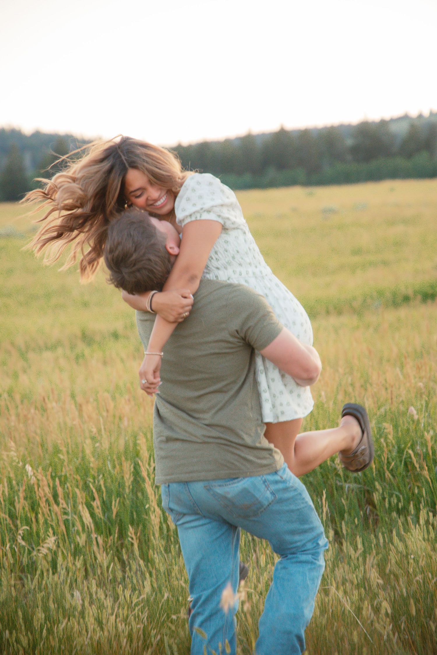 A joyful couple spins and dances in a sunlit meadow during golden hour.