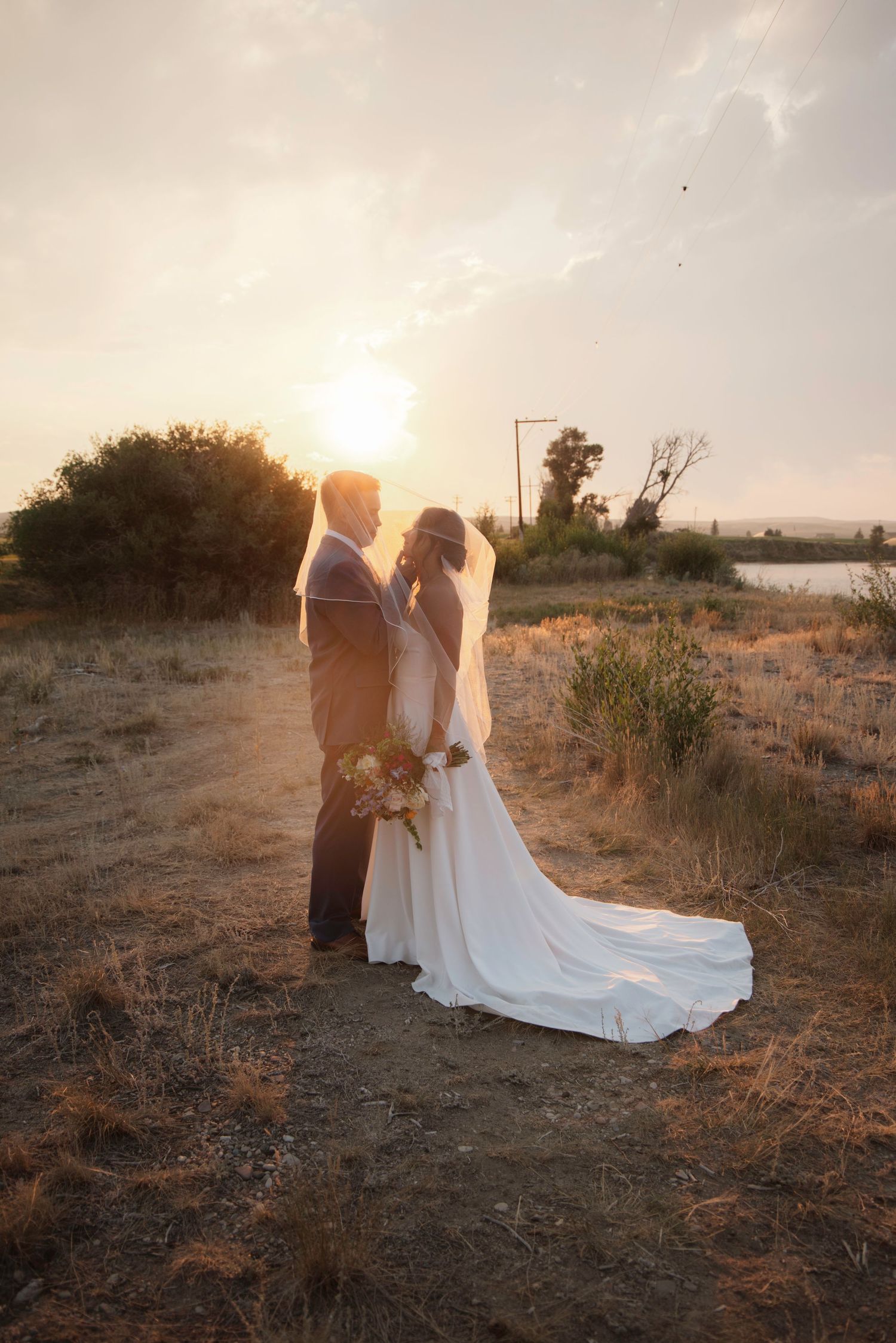 Couple in wedding attire photographed during golden hour in a desert landscape.