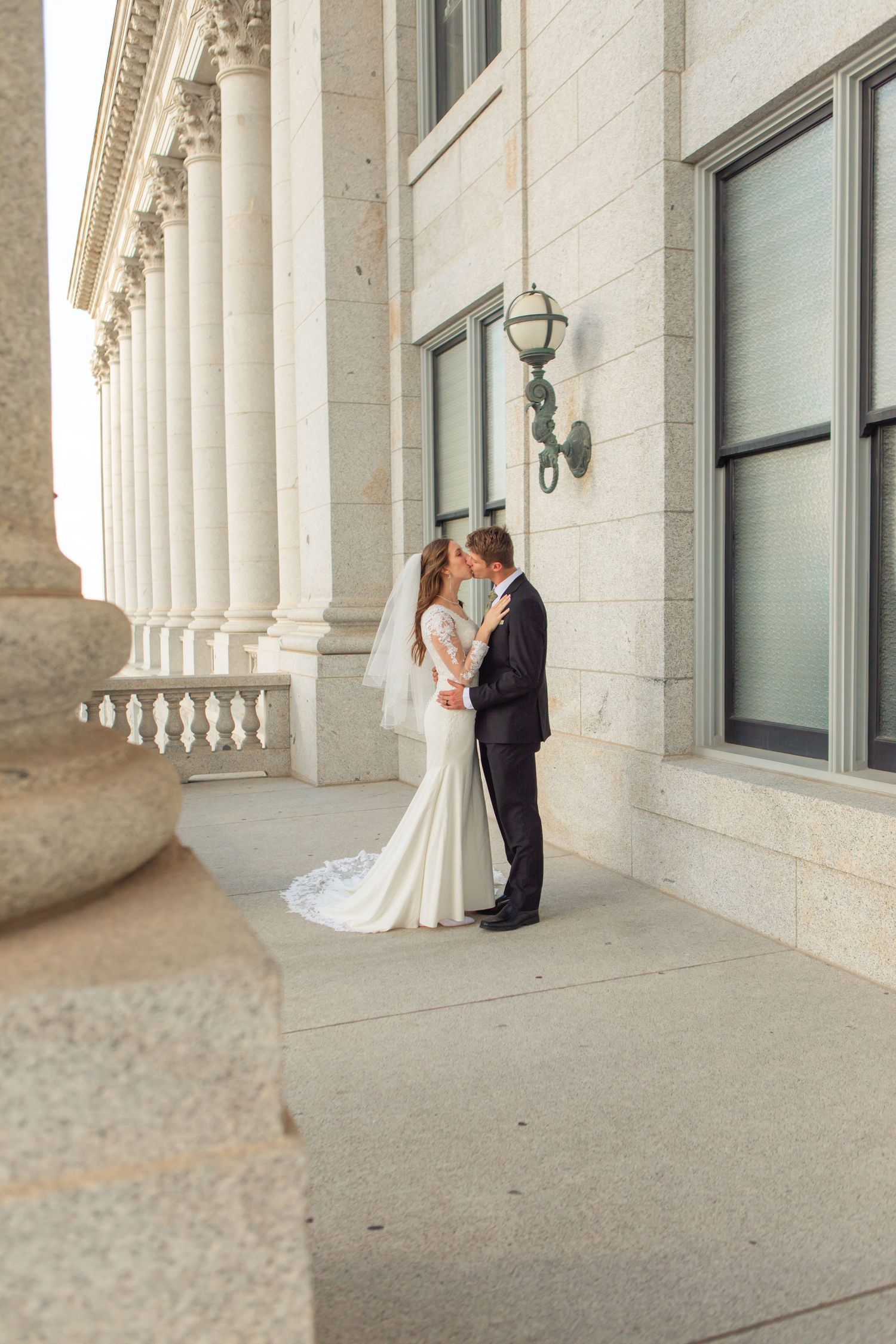 Wedding photos taken along a grand colonnade with white pillars and elegant architecture.