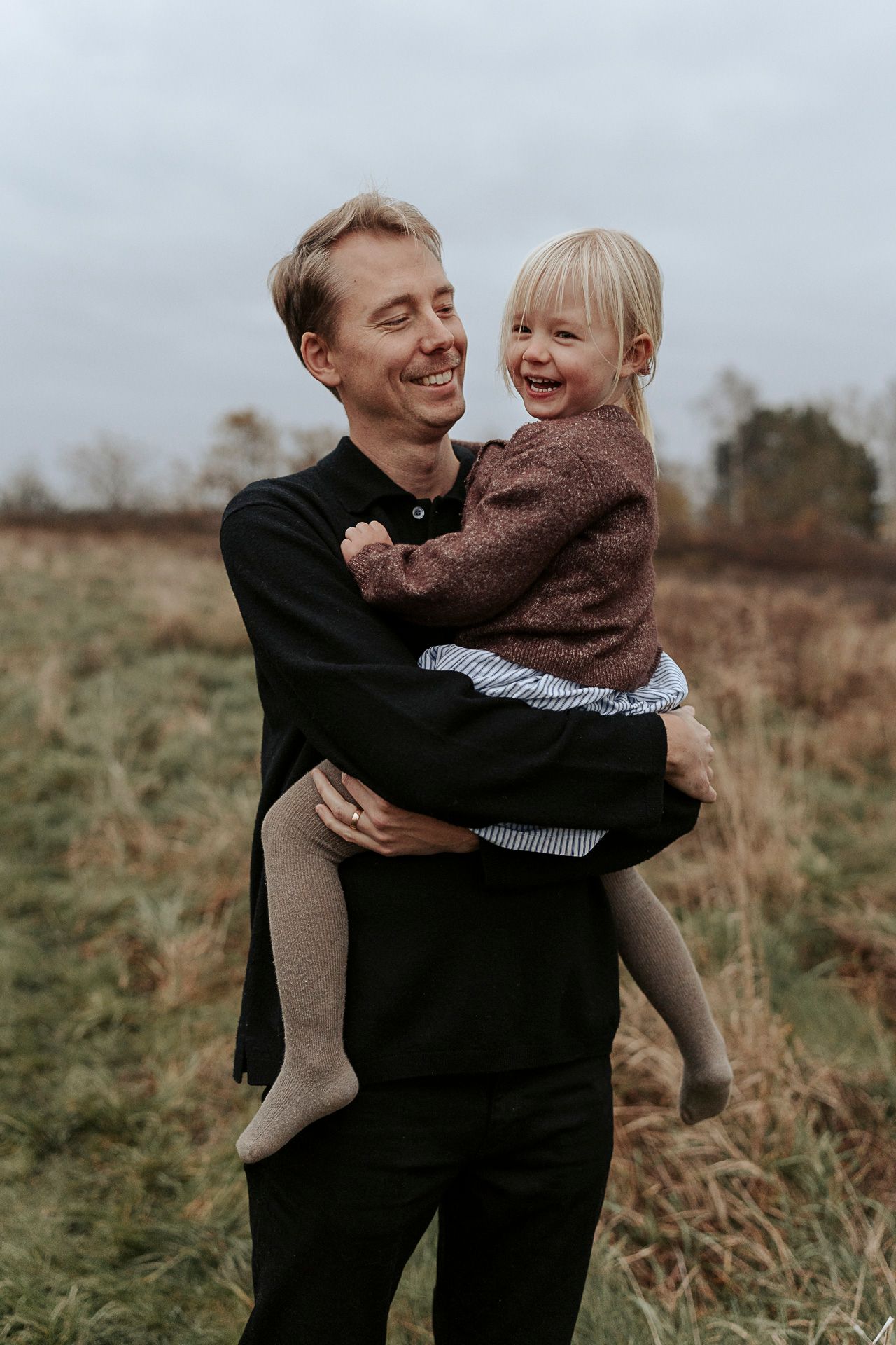 En pappa som håller sitt barn i famnen, de båda skrattar.