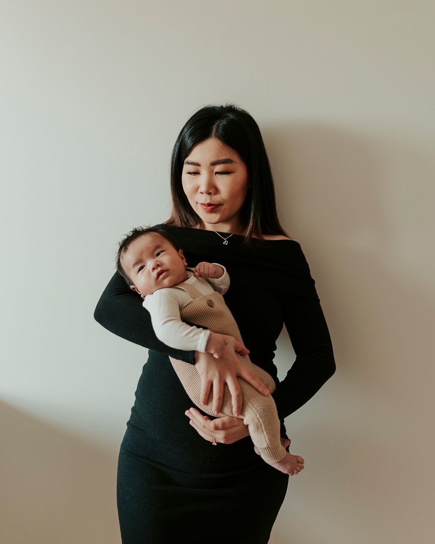 Mamma som står mot en vägg och håller sitt barn i famnen