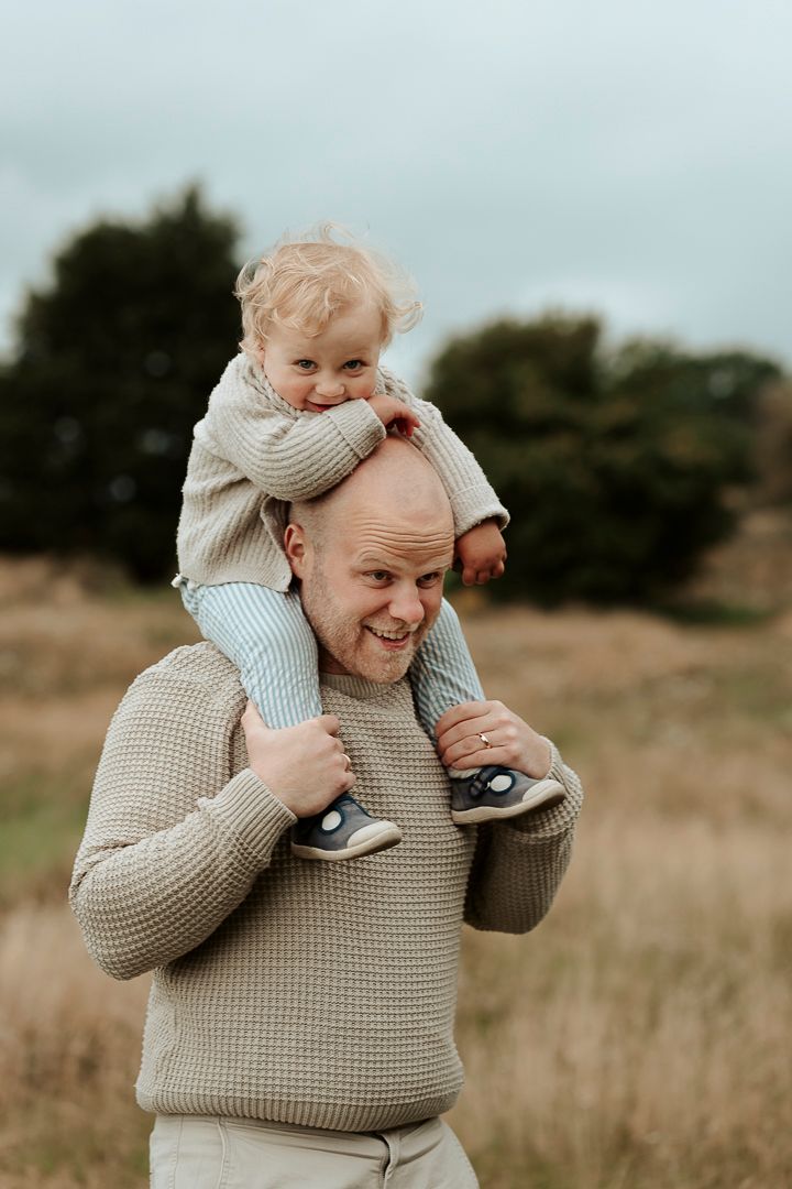 En pojke sitter på sin pappas axlar, de går på en äng i Kungsbacka.