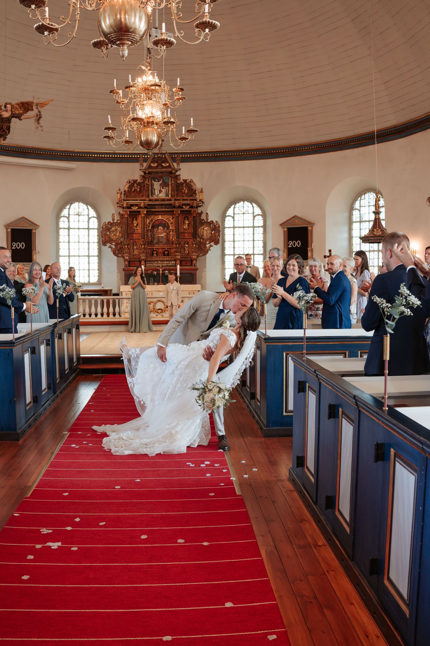 Brudpar efter sin vigsel, de kysser varandra i gången i kyrkan.