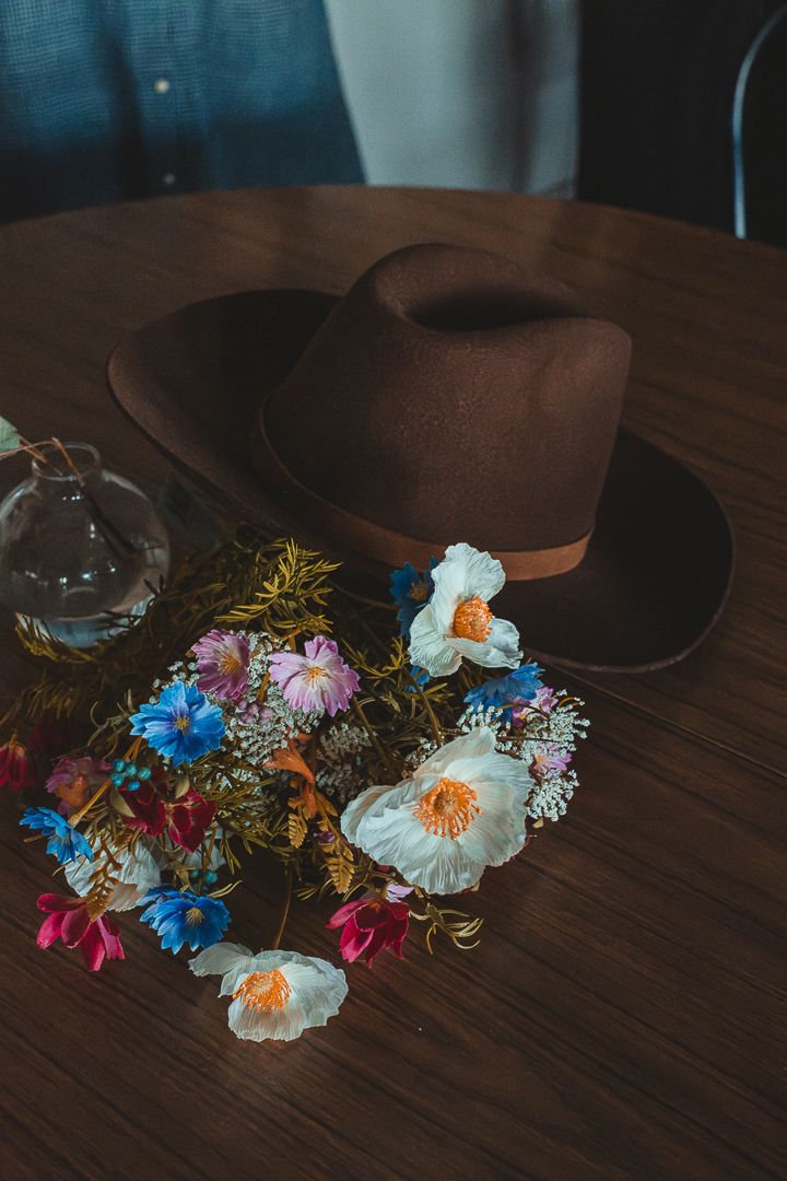 På ett bord ligger en cowboy hat och blommor