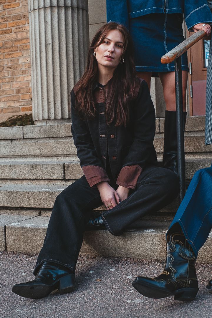En kvinna som sitter ned på en stentrappa, hon har på sig svarta jeans kläder