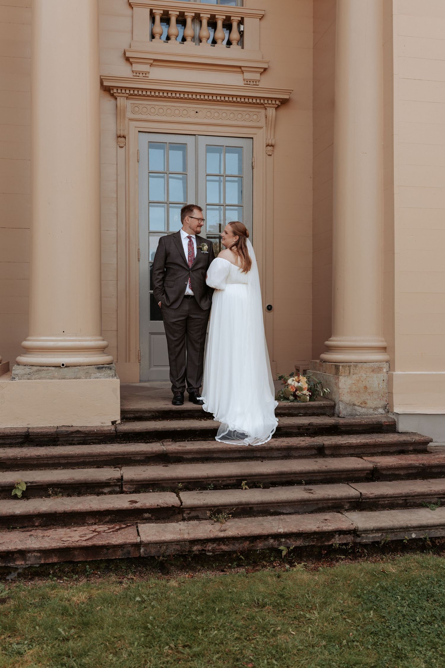 Ett brudpar står med varandra på en trappa vid ett slott.