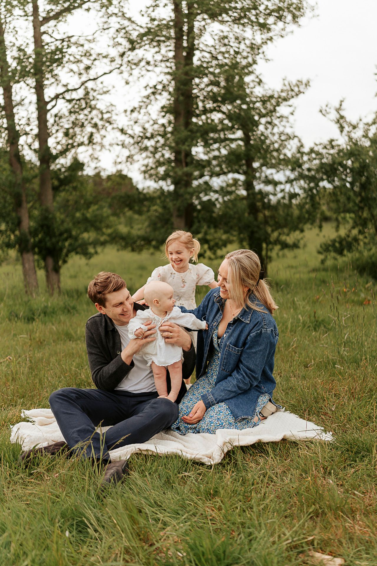 Familj som sitter på en filt tillsammans i en härlig grön miljö