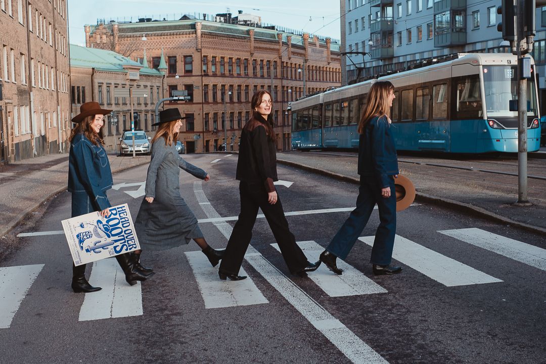 Fyra kvinnor som går över ett övergångsställe på rad i Göteborg. Den ena har en skylt i handen. I bakgrunden syns en spårvagn.