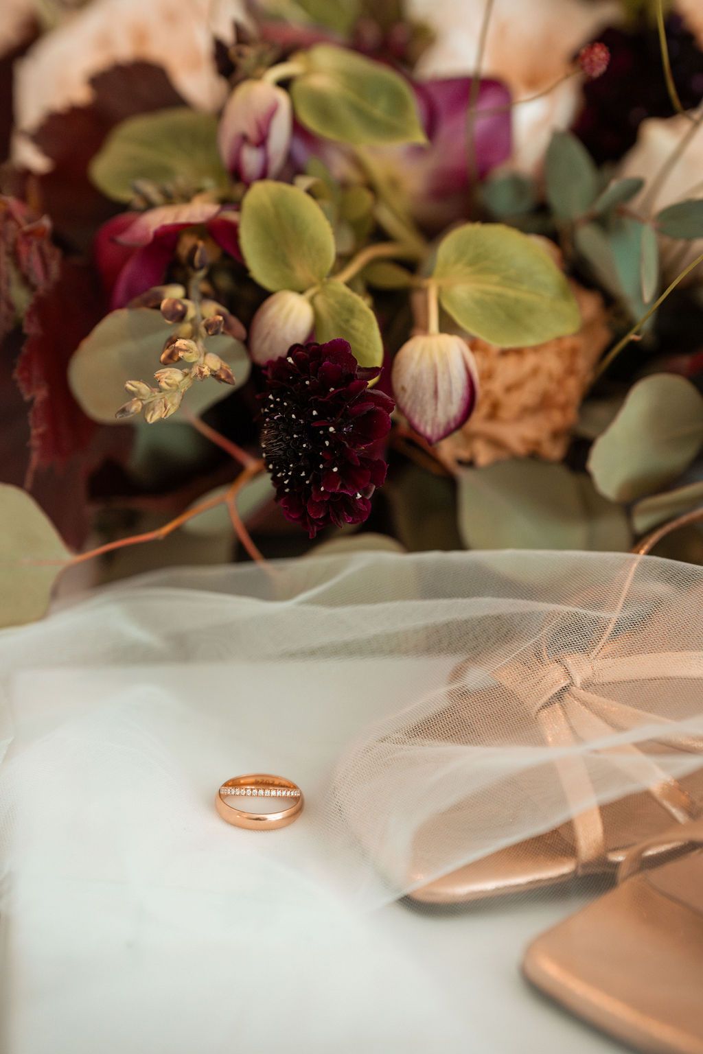 En detaljbild från en bröllopsfotografering med fokus på brudens ring, skor och brudbukett