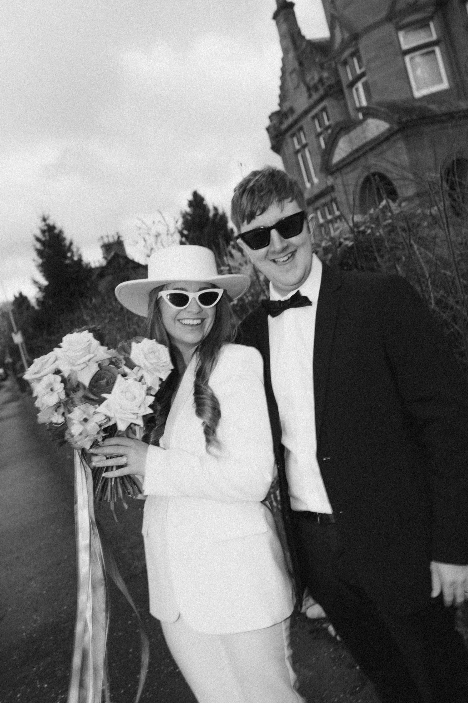 Wedding couple in sunglasses poses in black and white in front of a historic building. Aberdeen wedding photographer, wedding car elopement