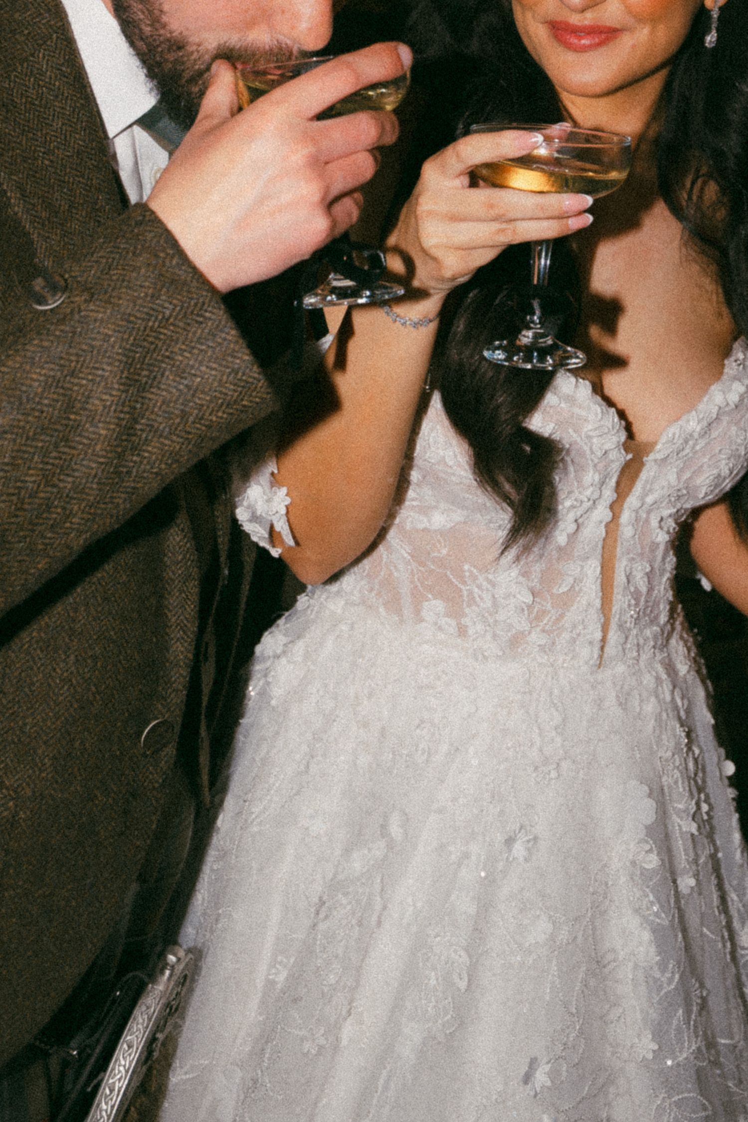 A wedding celebration scene featuring formal attire, champagne glasses, and elegant lace gown details.