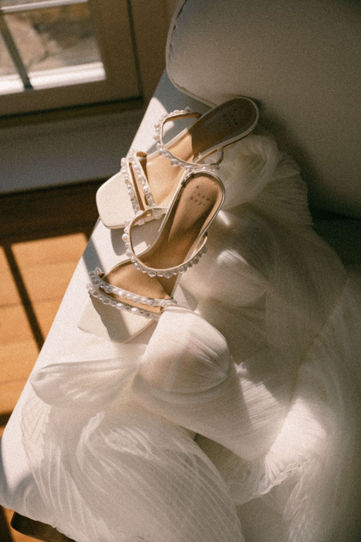 Elegant pearl-embellished bridal shoes resting on white tulle fabric in sunlight.  Aberdeen wedding photographer, carlogie house