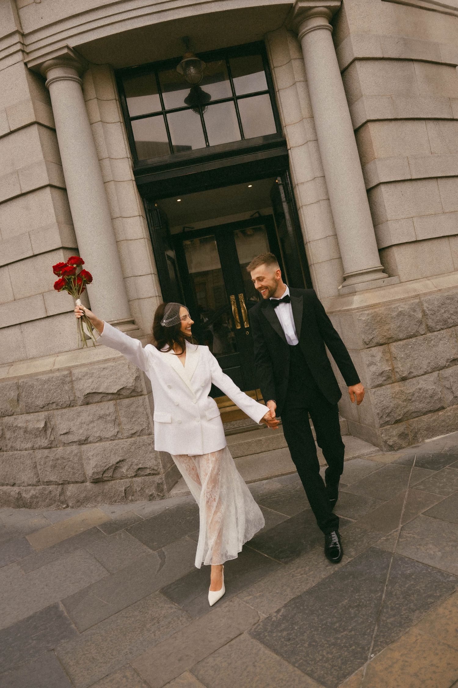 A series of outdoor wedding photos showing a couple posing playfully in front of a stone building with columns.