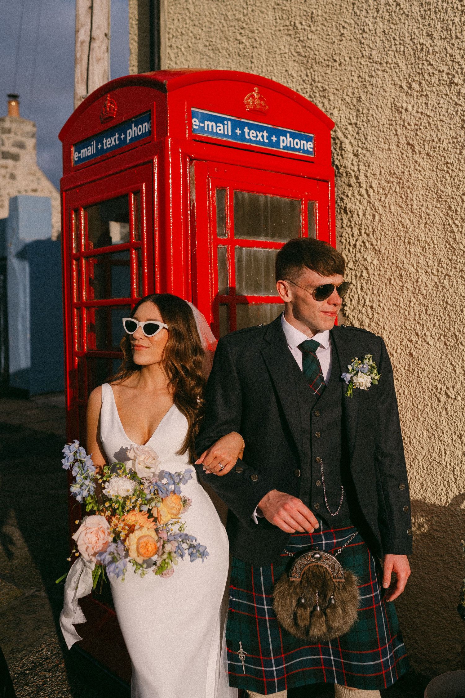 Newlyweds pose by a red British phone booth. Aberdeen wedding photographer,  seafield arms hotel Cullen